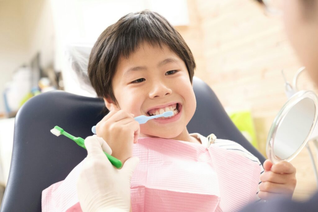 Young boy brushing teeth at dentist's office, promoting children's oral health habits for Wells Family Dental's Children's Dental Awareness Month blog