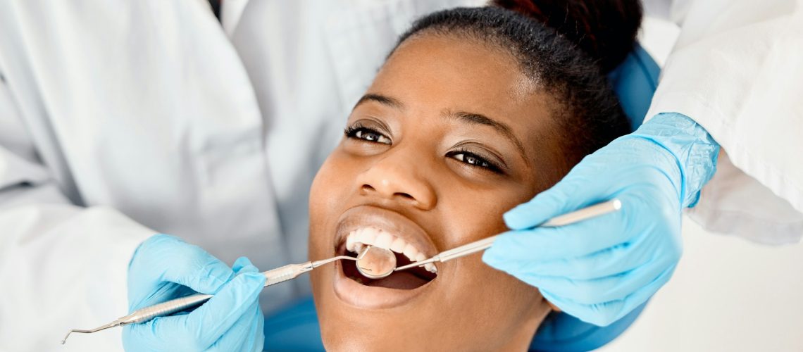 Dentist checking female patient's oral health during examination, emphasizing the importance of dental care.