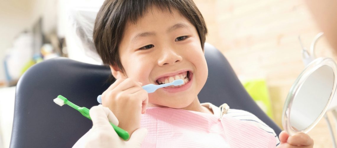 Young boy brushing teeth at dentist's office, promoting children's oral health habits for Wells Family Dental's Children's Dental Awareness Month blog