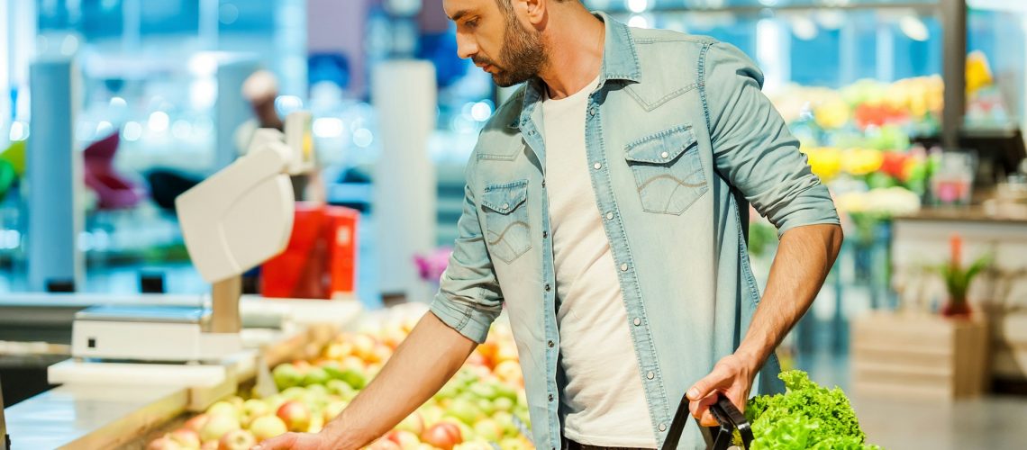 Man selecting fresh produce in grocery store, highlighting the link between nutrition and dental health, for Wells Family Dental's blog on diet's impact on oral health
